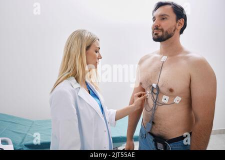 Der Kardiologe verfolgte den erwachsenen Mann mit Herzerkrankung mithilfe der Holter-Überwachung mit EKG-Sensoren Stockfoto