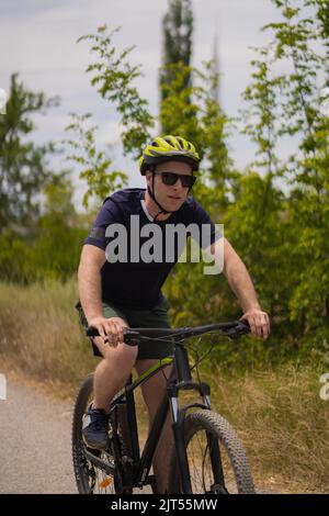 Porträt eines hübschen blonden Mannes, der mit dem Fahrrad unterwegs ist und den Tag genießt Stockfoto