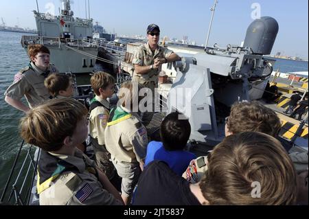 U.S. Navy LT. Top, der leitende Offizier des Küstenpatrouillenschiffs USS Whirlwind (PC 11), zeigt Boy Scouts während einer Schiffsbesichtigung am Mina Salman Pier 120107 ein MK38 Mod 2 25 mm Maschinengewehr-System Stockfoto