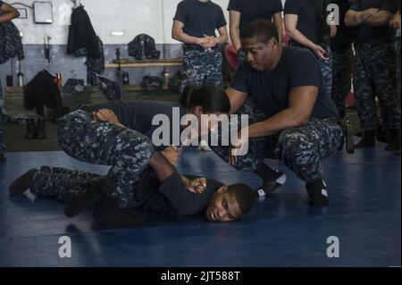 U.S. Navy Master-at-Arms 1. Class Right, zeigt Aviation Maintenance Administrationman 3. Class Left, und Culinary Specialist, wie man eine richtige 140118 durchführen kann Stockfoto