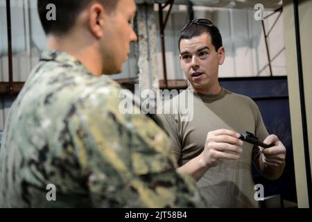 US Navy Mineman 1. Class Right, zugewiesen an Commander, Task Force (CTF) 56, erklärt die Eigenschaften einer M4 Karabinerbolzen-Montage während des Waffentrainings bei Naval Support Activity Bahrain 140212 Stockfoto