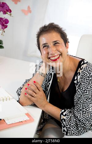 Eine fröhliche, fröhliche Frau, die zu Hause sitzt und arbeitet Stockfoto