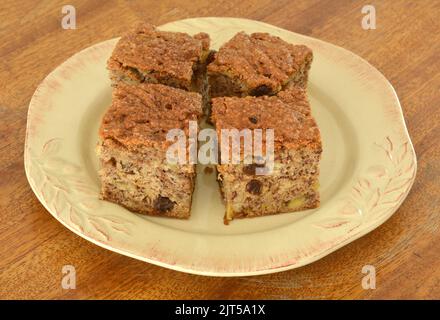 Frisch gebackenes Bananenbrot mit Rosinen und Zimtzucker-Belag. Auf rustikalem gelbem Teller und altem verzweifeltem Holzhintergrund. Horizontales Format. Stockfoto