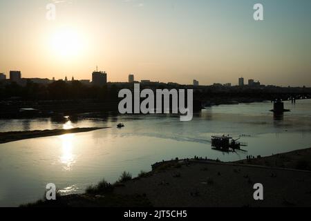 Warschau, Polen. 26. August 2022. Die Sonne scheint über der Skyline der Stadt, während am 26. August 2022 ein Ponton auf der Weichsel in Warschau, Polen, zu sehen ist. Obwohl die Durchschnittstemperatur in Polen im August in den letzten Wochen etwas über 19 Grad Celsius beträgt, haben die Temperaturen täglich Höchststände von mehr als 30 Grad erreicht. (Foto von Jaap Arriens/Sipa USA) Quelle: SIPA USA/Alamy Live News Stockfoto