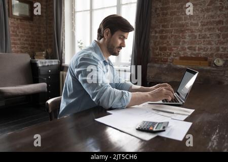 Fokussierter freiberuflicher Geschäftsmann, der zu Hause Buchhaltung macht Stockfoto