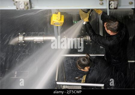 US-Matrosen mit dem Executive Leadership Development Program kämpfen gegen Lecks im Damage Control Wet Trainer während einer Tour durch die Submarine Learning Center-Abteilung San Diego am 13. Januar 2014 140113 Stockfoto