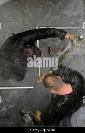 US-Matrosen mit dem Executive Leadership Development Program kämpfen gegen Lecks im Damage Control Wet Trainer während einer Tour durch die Submarine Learning Center-Abteilung San Diego am 13. Januar 2014 140113 Stockfoto