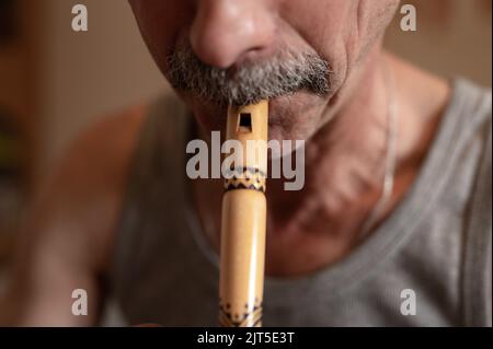 Älterer Flötenspieler. Gesichtsloser, unprofessioneller Mann von älteren kaukasischen Blockflötisten Menschen mit Schnurrbart mit Mund und Lippen spielen auf pfeifenamat Stockfoto