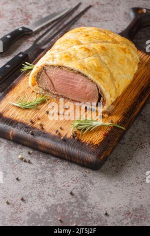 Perfektes hausgemachtes saftiges Rind Wellington, Filet-Gericht auf rustikalem Holzbrett auf dem Tisch. Vertikal Stockfoto