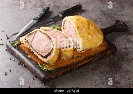 Köstliches frisch gekochtes Rindfleisch wellington mit Pilzduxelle und Puffkruste Nahaufnahme auf einem Holzbrett auf dem Tisch. Horizontal Stockfoto