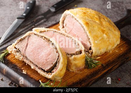 Medium Beef Wellington, klassisches Steak in Scheiben, Nahaufnahme auf rustikalem Holzbrett. Horizontal Stockfoto