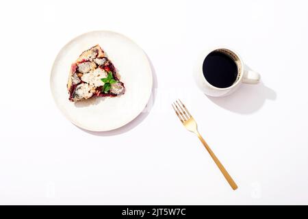 Eine Tasse Kaffee und Pflaumenkuchen auf dem weißen Tisch. Frühstückskonzept. Draufsicht, flach liegend. Stockfoto