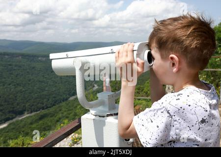 Das Kind blickt vom Una-koz-Grat, Adygea, durch ein Fernglas auf das Tal des Flusses Belaya Stockfoto