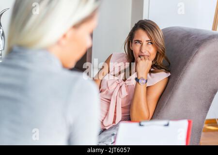 Frau bei der Therapiesitzung. Aufmerksamer Psychologe. Junge Frau bei der Psychotherapie, die über Ratschläge nachdenkt, die sie erhalten hat Stockfoto