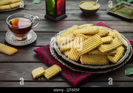 Cookies zur Feier des islamischen Festes El Fitr (das Fest, das nach dem Ramadan kommt).köstliche traditionelle Kekse mit einer Tasse Tee serviert. Stockfoto