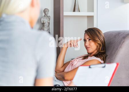 Frau bei der Therapiesitzung. Aufmerksamer Psychologe. Junge Frau bei der Psychotherapie, die über Ratschläge nachdenkt, die sie erhalten hat Stockfoto