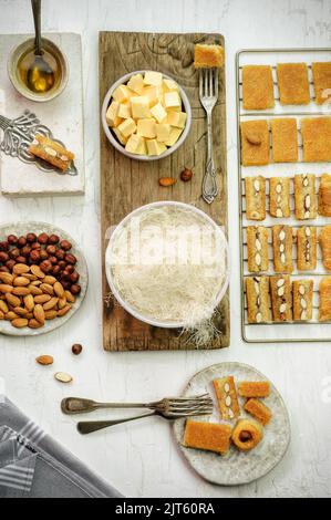 Arabische Küche; Sorten von Nahost-Gebäck und Ramadan Desserts Kunafa mit Butter, frischen Kunafa, gerösteten Nüssen und Honig platziert. Stockfoto
