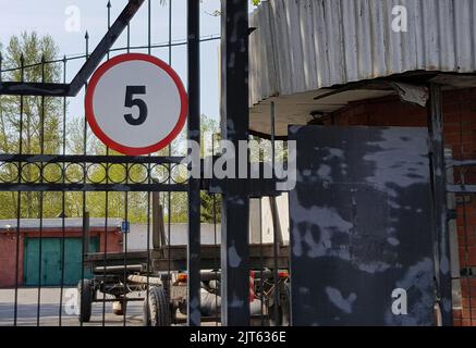 Bewachter Eingang zum Industrieparkhaus, umgeben von einem Stahlzaun. Am Tor ist ein Schild, das die Geschwindigkeit auf 5 km begrenzt Stockfoto