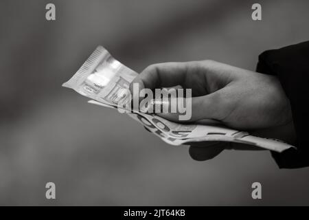 Eine Nahaufnahme in Graustufen mit Details auf einer Hand, die Euro-Banknoten hält Stockfoto