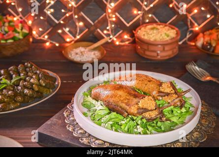 Arabische Küche, traditionelle ägyptische gefüllte Tauben oder Hamam Mahshi-Gericht. Serviert mit grünem Salat, orientalischen Gurken, Weinblättern und gekochtem Freekeh. Stockfoto