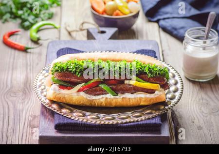 Arabische Küche, traditionelles ägyptisches Würstchen-Sandwich oder „Alexanderische Wurst“. Serviert mit Gurken und Tahini-Sauce. Nahaufnahme mit Kopierbereich. Stockfoto