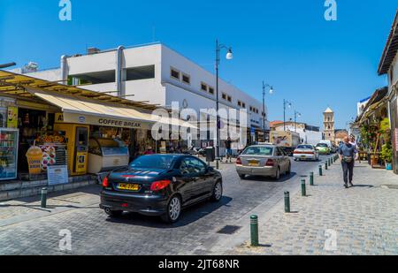 Larnaca, Zypern - 22. April 2022 - Autos und Geschäfte im Zentrum von Larnaca im Sommer unter blauem Himmel Stockfoto