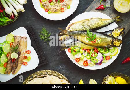 Mediterrane Küche, geräucherter Heringsfisch serviert mit grünen Zwiebeln, Zitrone, Chili, Salat, Gewürzen, Pita-Brot und Tahini-Sauce. Stockfoto