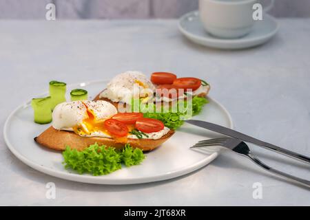 Pochiertes Eiertoast mit Tomaten und Frischkäse und Brot auf einem Teller. Gesundes Lebensmittelkonzept. Stockfoto