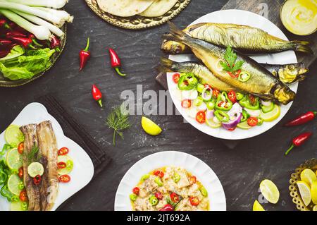 Mediterrane Küche, geräucherter Heringsfisch serviert mit grünen Zwiebeln, Zitrone, Chili, Salat, Gewürzen, Pita-Brot und Tahini-Sauce. Stockfoto