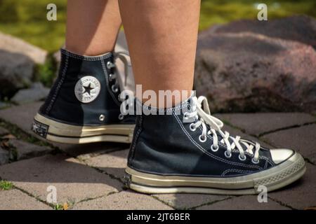 Nahaufnahme von schwarzen Chucks, die von einer jungen Frau getragen werden Stockfoto
