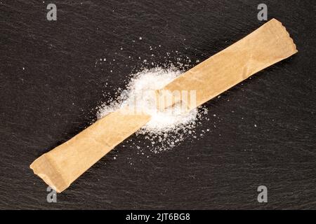 Ein Papierabfluss mit Zucker auf Schieferstein, Nahaufnahme, Draufsicht. Stockfoto