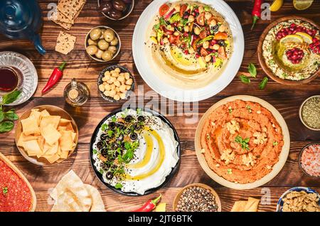 Arabische Küche: Sorten von köstlichen Meze und Dips aus dem Nahen Osten. Hummusplatte, Muhammara, Labneh, baba ghanough, Harissa und Oliven. Stockfoto