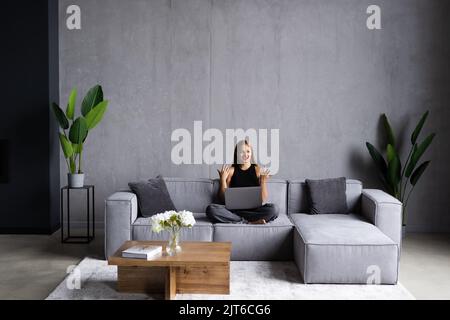 Junge glückliche Frau, die einen Videoanruf hält und Freunde, Verwandte oder Eltern hallo stotet. Attraktive Bloggerin, die neue Videos für Follower aufzeichnet. Stockfoto