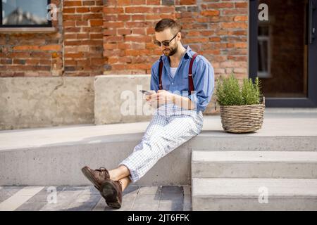Stilvoller Mann mit Telefon auf der Straße Stockfoto