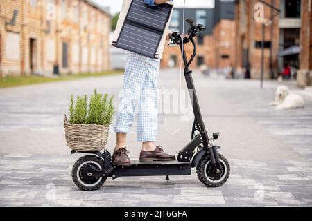 Stilvoller Kerl fährt Elektroroller und nutzt Handy unterwegs Stockfoto