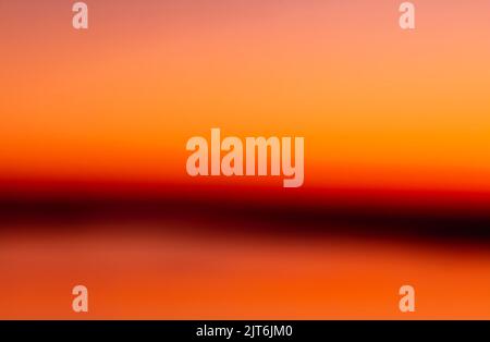 Abstrakter, rosa-oranger Hintergrund mit dunklen Streifen am Horizont. Verwischen Sie pastellfarbenen süßen verträumten Hintergrund. Pink orange Bokeh aus Fokus Natur Stockfoto