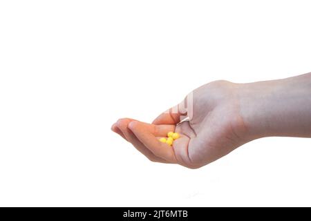 Isolierte Handfläche voller gelber Pillenkapseln mit weißem Hintergrund. Stockfoto