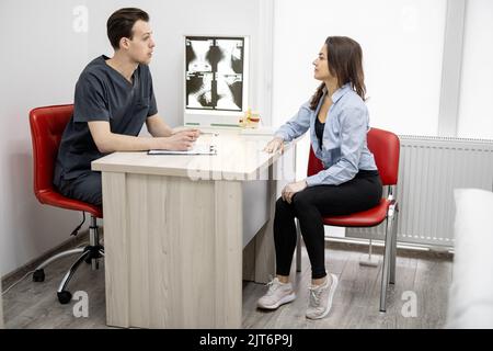Junge Frau in Absprache mit einem Physiotherapeuten in der Arztpraxis Stockfoto