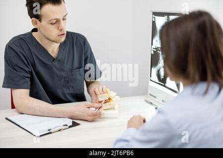 Junge Frau in Absprache mit einem Physiotherapeuten in der Arztpraxis Stockfoto