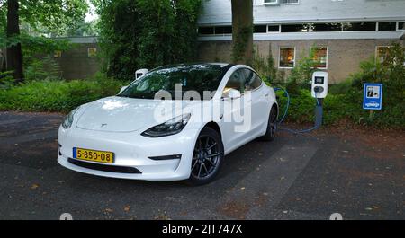 Amersfoort, Niederlande - August 28 2022 Ein weißes Testa Modell 3 wird geladen. Dies ist eine kompakte Executive Limousine, die batteriebetrieben ist. Es ist an der m Stockfoto