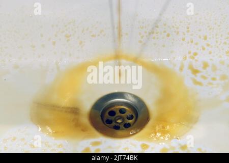 Rostiges, schmutziges Wasser fließt in einem Waschbecken aus einem Wasserhahn Stockfoto