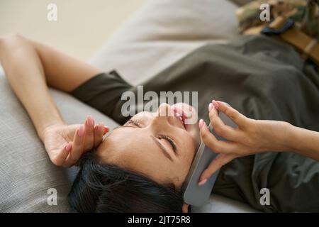 Soldatin, die sich auf dem Sofa ausruht und auf dem Mobiltelefon spricht Stockfoto