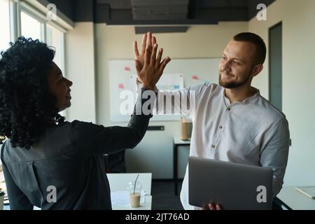 Fröhlicher Mann und Frau geben fünf für den Projektsieg Stockfoto