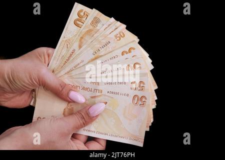 Frau mit türkischer Lira auf schwarzem Hintergrund, sichtbare Hände türkische Währung von 50 Banknoten, Finanzkonzept. Stockfoto