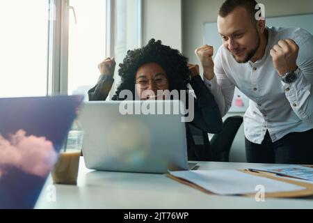 Büroangestellte am Computer freuen sich über einen erfolgreichen Deal Stockfoto