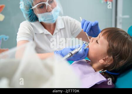 Der Zahnarzt führt ein Zahnpolierverfahren an jungen weiblichen Patienten durch Stockfoto