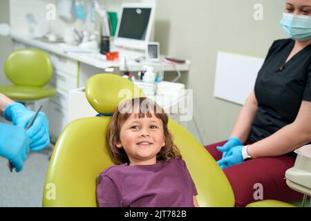 Fröhliches weibliches Kind posiert für Kamera im Stomatologen Büro Stockfoto