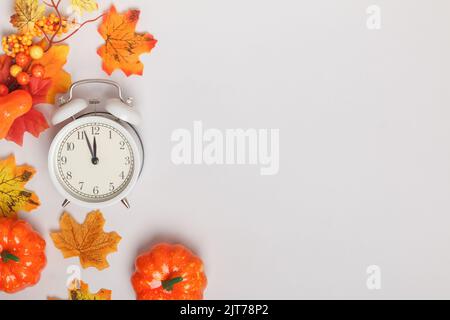 Wecker mit heruntergefallenen Blättern, Kürbissen. Übergang ändern Herbst Zeit Transformation, Wechsel der Jahreszeiten. Raum kopieren Stockfoto
