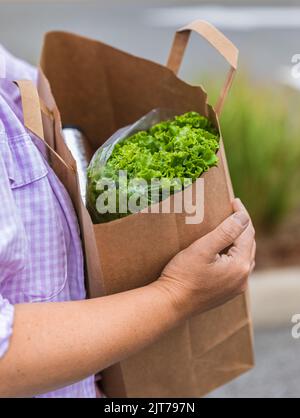 Eine gesunde Tasche tragen. Zugeschnittenes Bild einer Frau, die einen Papierbeutel mit frischem Gemüse in der Hand hält. Lebensmittelbeutel mit frischen und gesunden Lebensmitteln Stockfoto