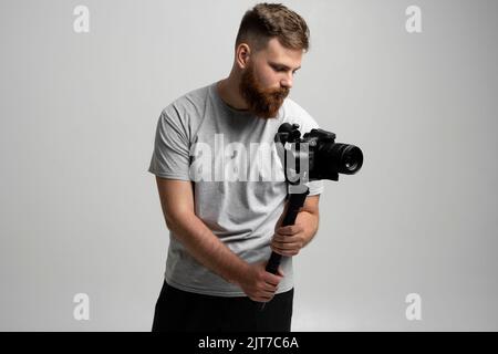 Professioneller Content Creator mit einer dslr-Kamera auf 3-Achsen-Gimbal-Stabilisator. Filmemachen, Videografie, Hobby- und Kreativitätskonzept. Stockfoto